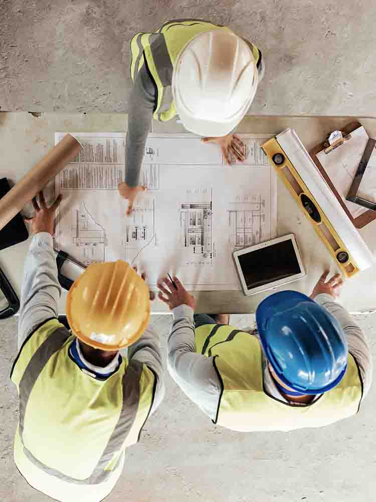construction workers looking at blueprints spread across a table