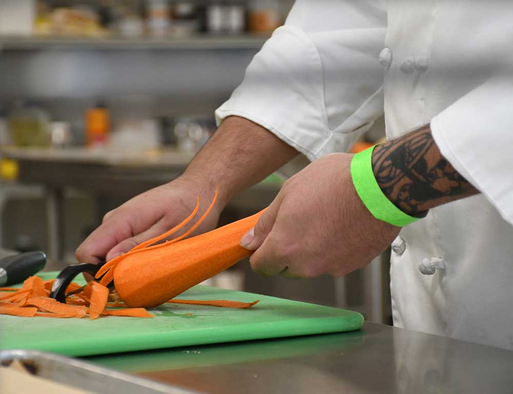 Culinary Arts student cutting a carrot