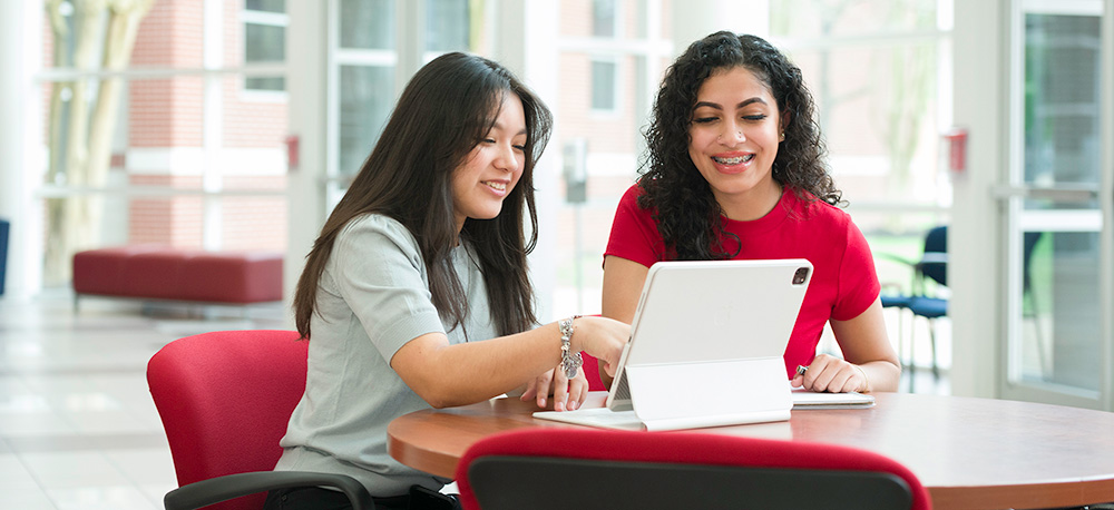 two girls collaborating on laptop